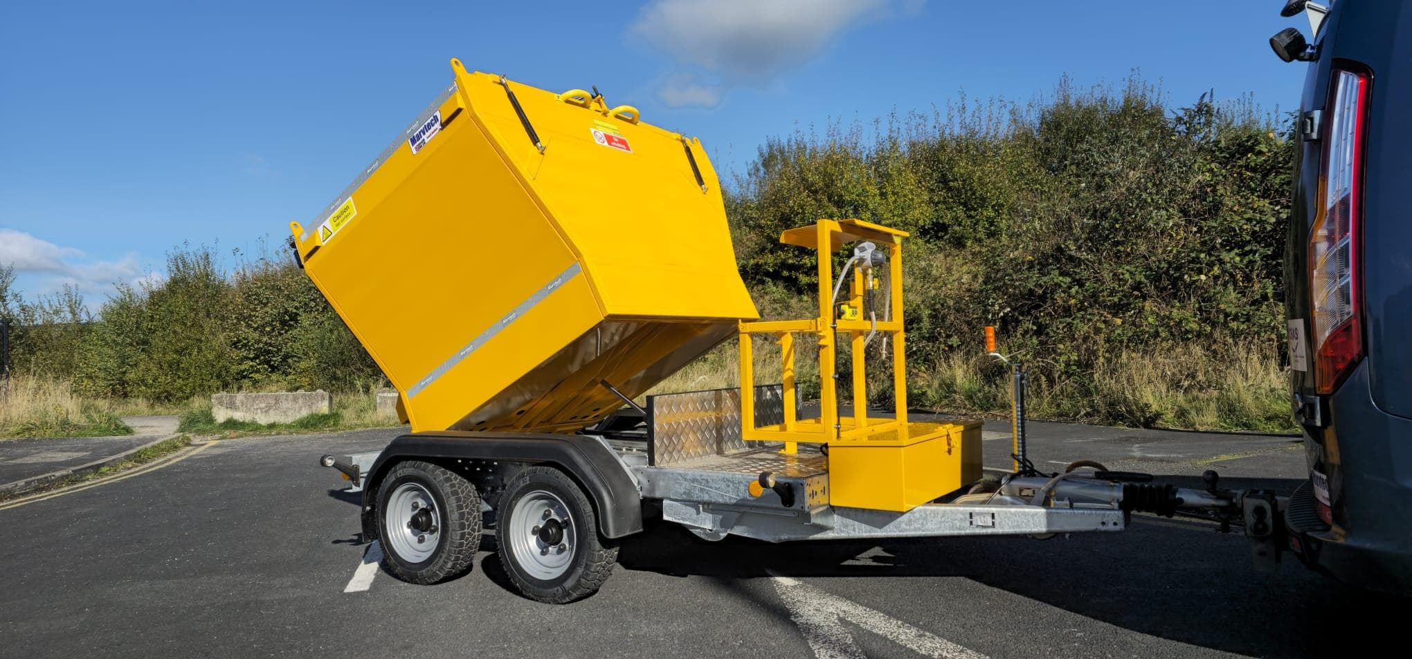 Towable Hotbox with the hopper tipped up on a twin-axle trailer